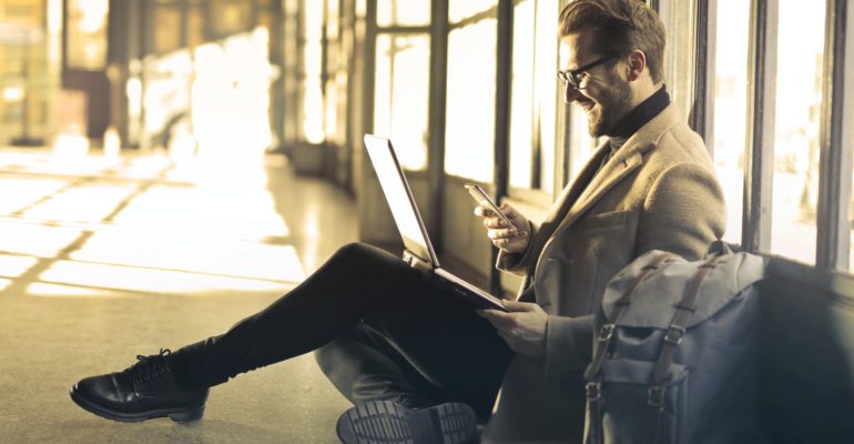 Man smile in front of phone and computer